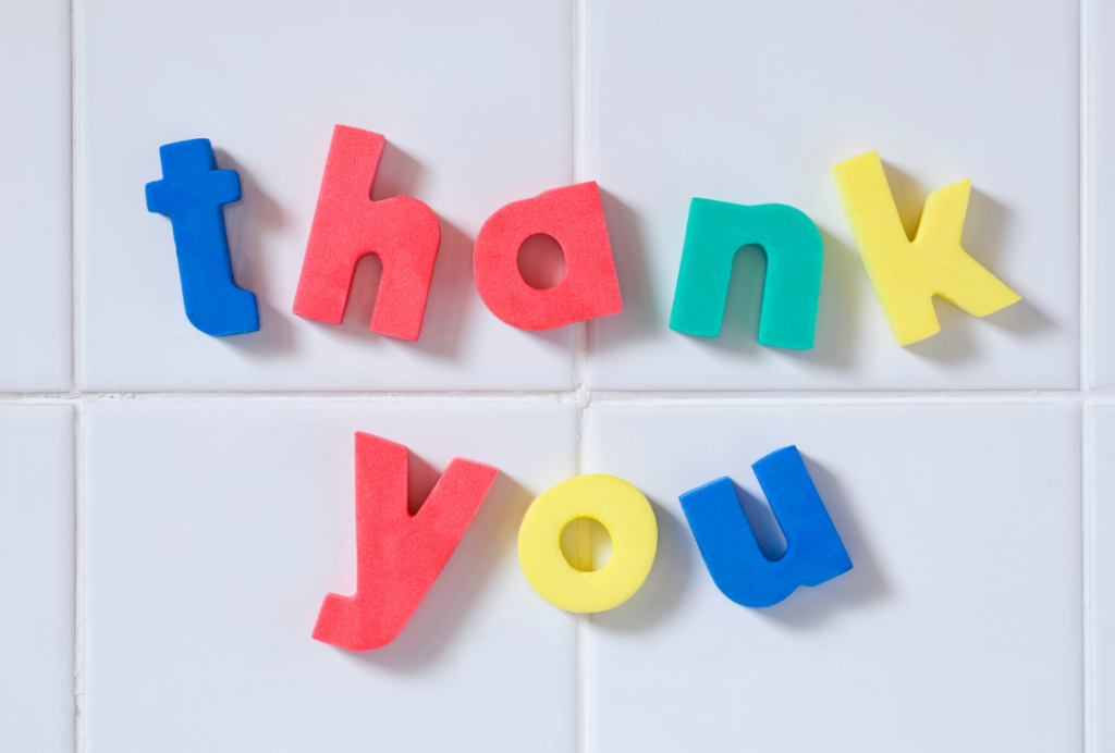 The word thank you spelt in colourful magnetic letters, stuck to tiles.
