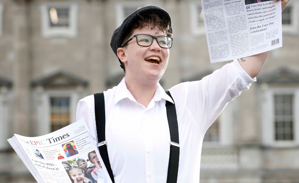 Young man holding up The EPIC Times newspaper outside Leinster House