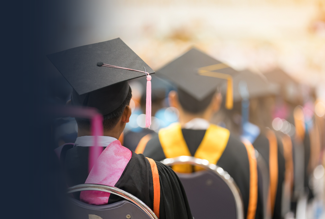 A photo of students in graduation gowns taken from behind them.