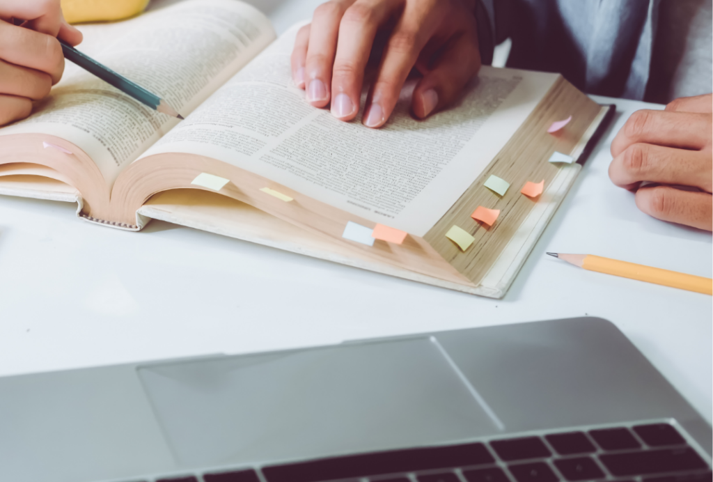 Two people studying a book, their hands are in view
