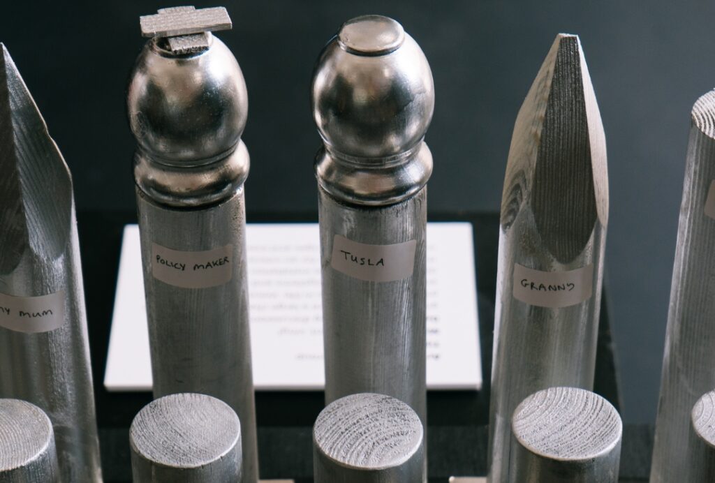 Wooden sculpture pieces painted silver and labelled “Policy Maker”, “Tusla”, and “Granny”, displayed as part of an artwork.