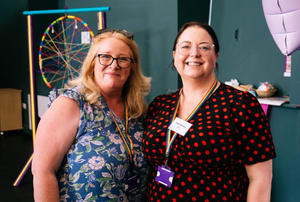 Two EPIC staff members wearing name badges and rainbow lanyards stand side by side.
