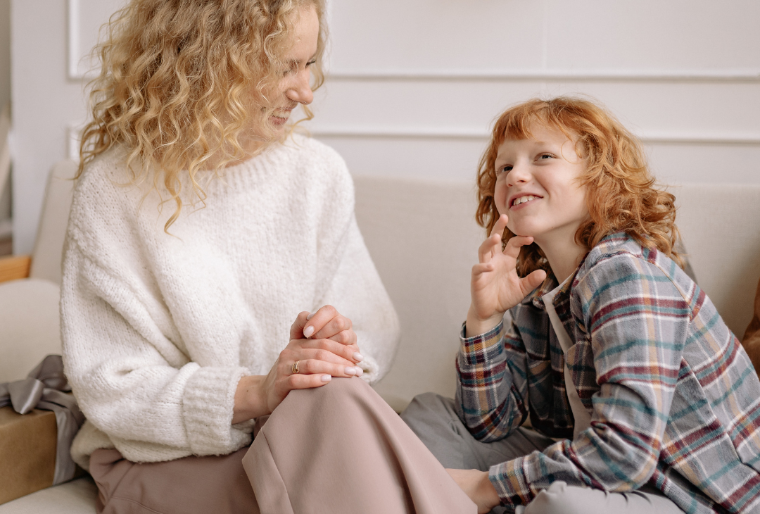 Adult sitting on couch talking to a child.